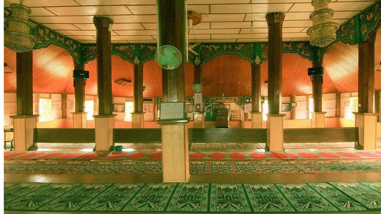 Interior Masjid Tuo Balai Nan Duo Payakumbuh dengan tiang kayu besar dan karpet hijau bermotif khas Minangkabau